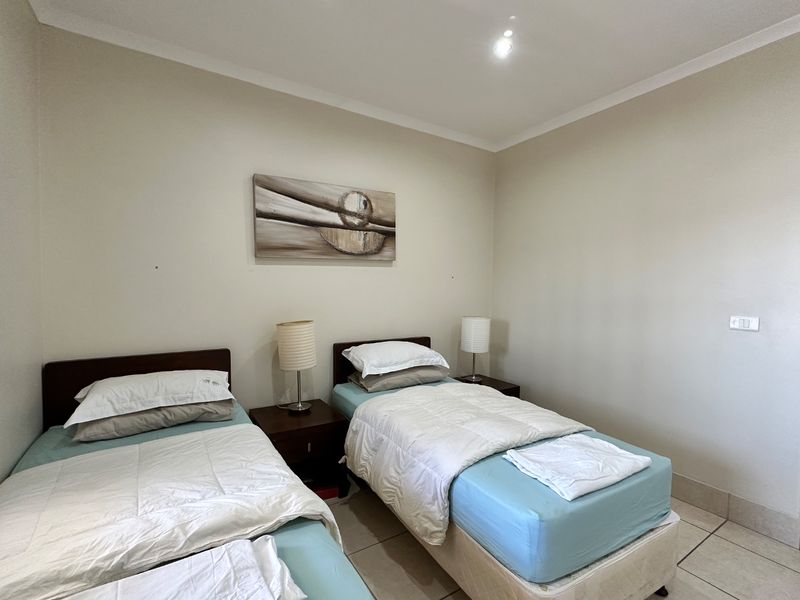 A functional bedroom featuring neutral wall tones, tiled flooring, and cove cornice detailing, providing a clean and simple space.