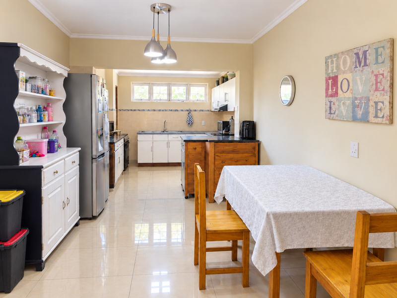 Open-plan kitchen and dining area featuring tiled flooring, ample cabinetry, granite countertops, and integrated appliances, creating a functional and connected living space.