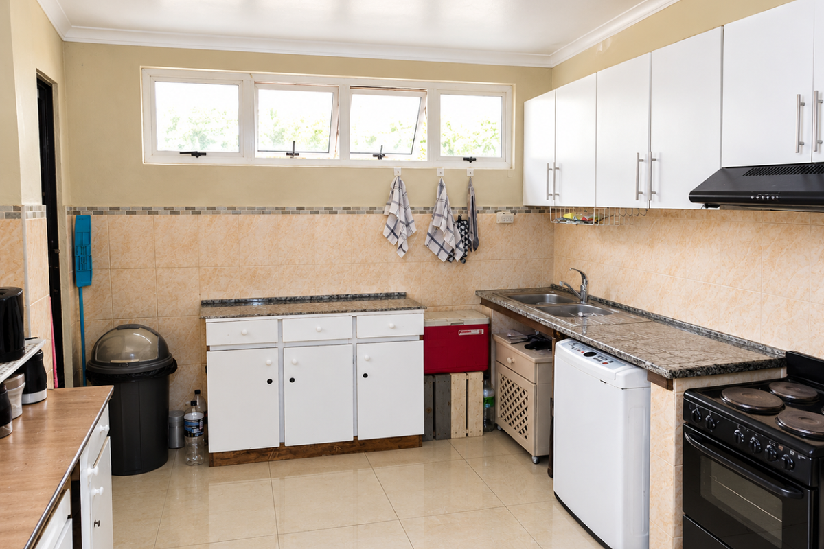Functional kitchen featuring granite countertops, white cabinetry, double basin sink, and built-in electric stove with extractor fan, finished with tiled backsplash and flooring.