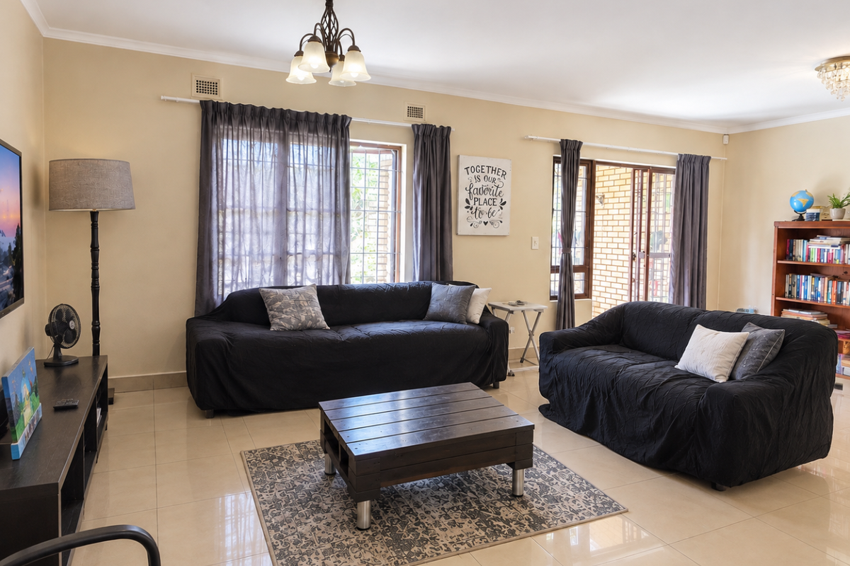 Spacious living room featuring neutral tiled flooring, large windows with security bars, and direct access to an outdoor area through a sliding glass door.