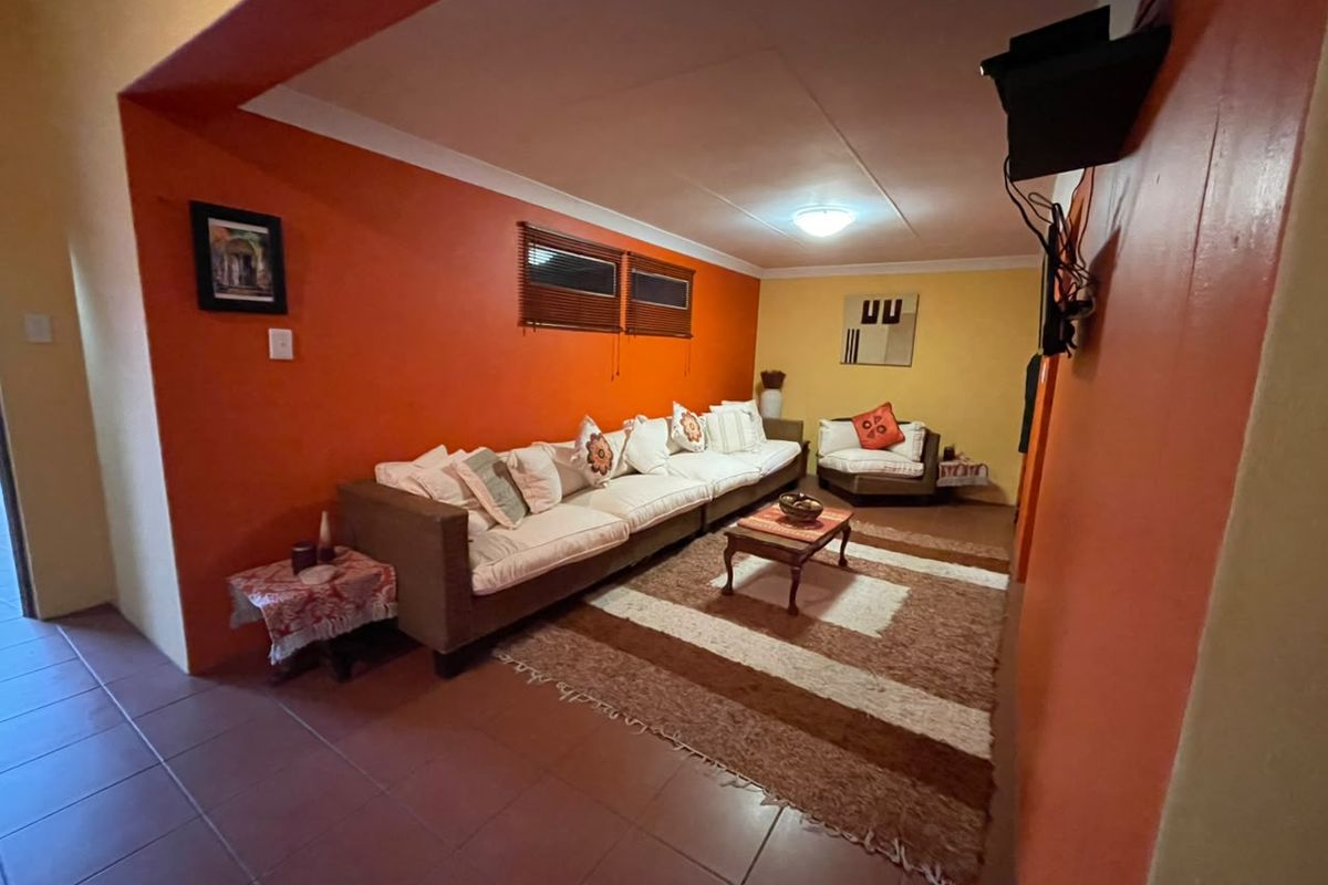 A living room featuring tiled flooring, warm-toned walls, and venetian blinds, providing a functional and lived-in space.