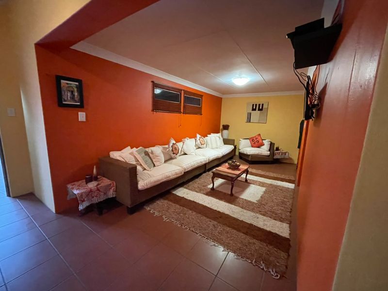A living room featuring tiled flooring, warm-toned walls, and venetian blinds, providing a functional and lived-in space.