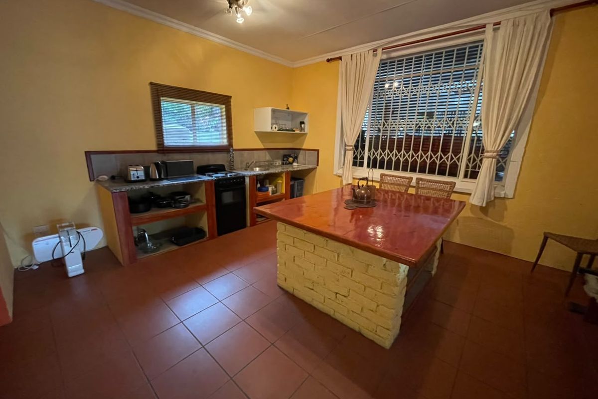 A dated kitchen featuring a central brick island, tiled flooring, and built-in shelving, offering potential for a modern renovation.