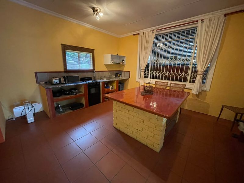 A dated kitchen featuring a central brick island, tiled flooring, and built-in shelving, offering potential for a modern renovation.