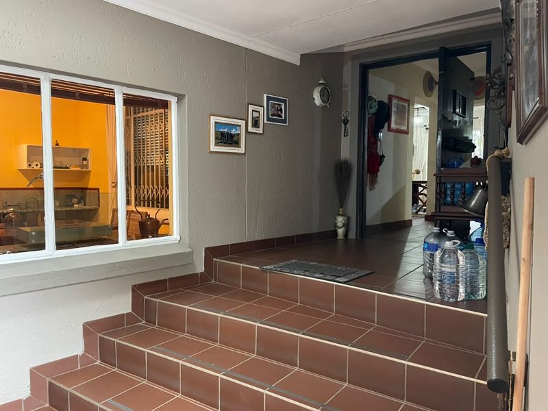 Covered entrance area featuring tiled steps leading to the main doorway, with a view into the interior living space through a large window.