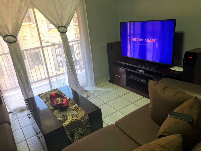 A living room area featuring tiled flooring and a sliding glass door providing access to an outdoor balcony space.