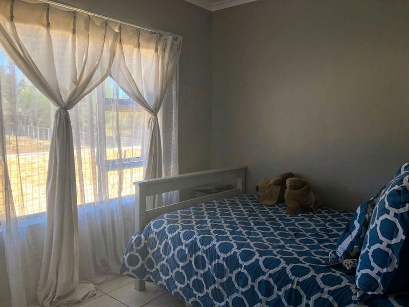 A functional bedroom featuring tiled flooring and a large window with natural light, providing a comfortable space for rest.