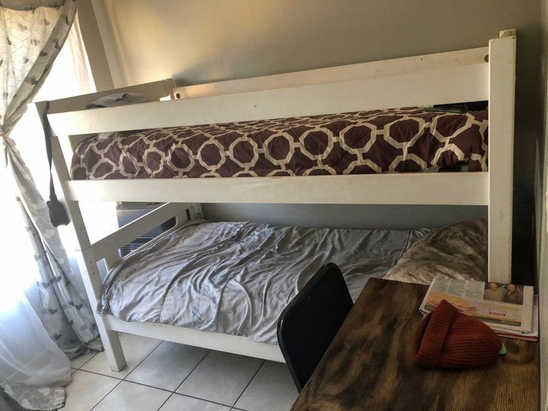 A compact bedroom featuring tiled flooring and space for a bunk bed setup, suitable for a child's room or guest accommodation.