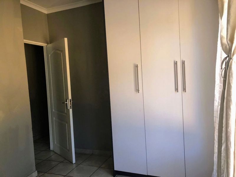 A bedroom featuring built-in cupboards and tiled flooring, providing a clean and functional space ready for personalization.