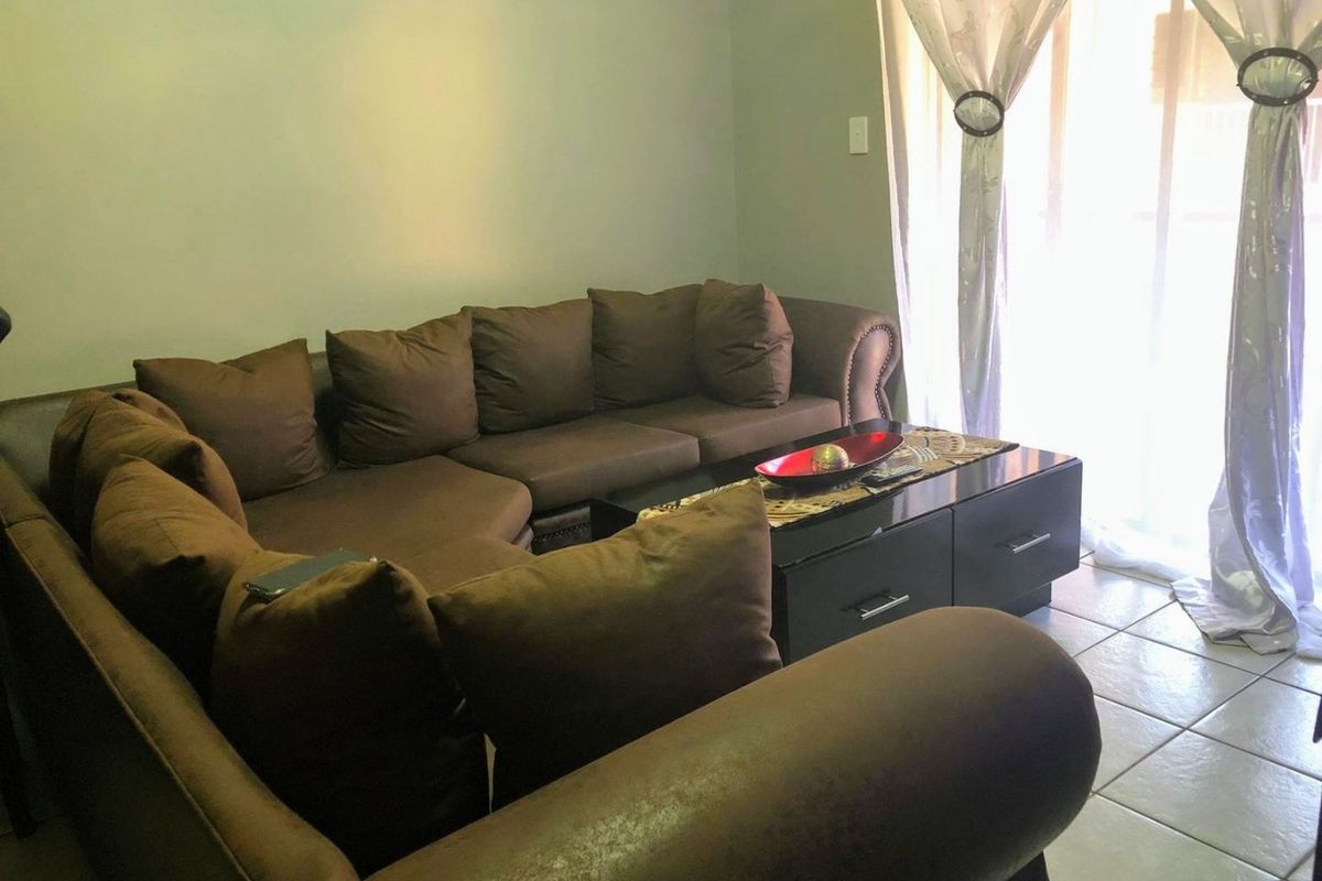 A living room area featuring tiled flooring and a sliding glass door providing access to the exterior.