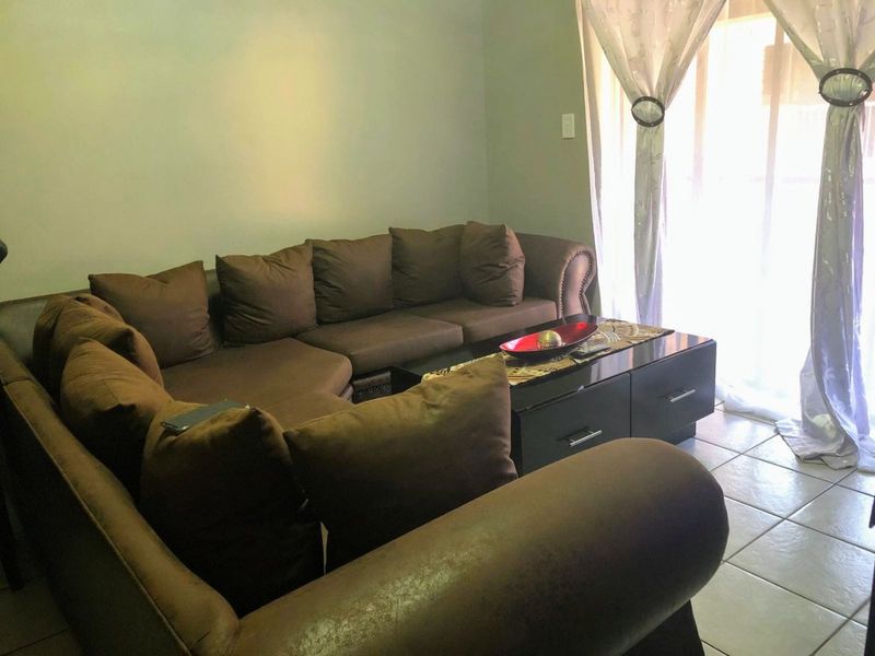 A living room area featuring tiled flooring and a sliding glass door providing access to the exterior.