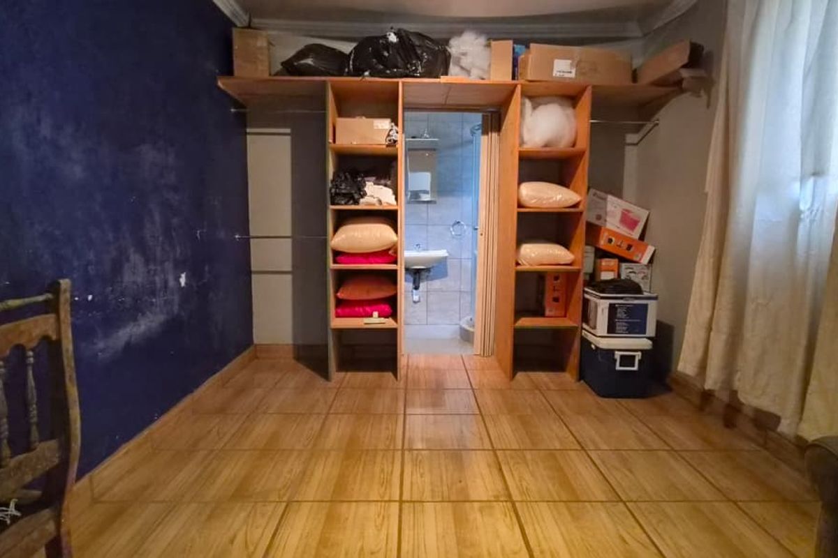 Bedroom featuring tiled flooring, built-in shelving units, and direct access to an en-suite bathroom.
