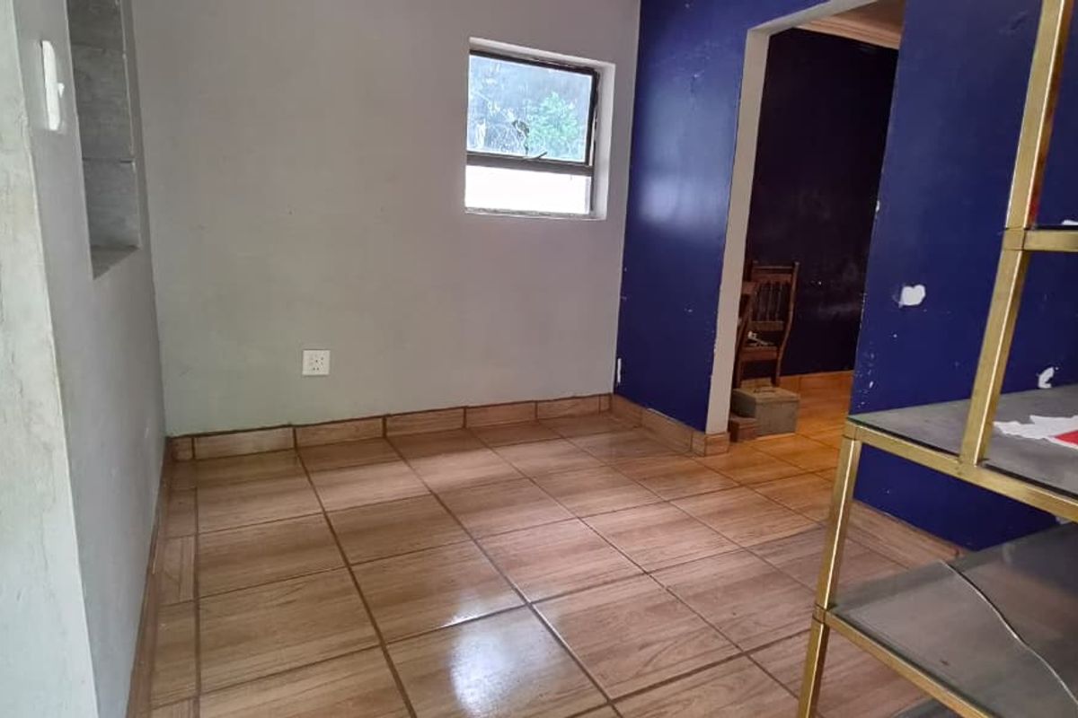 An empty living area featuring tiled flooring and unfinished wall surfaces, offering a blank canvas for renovation and interior design updates.