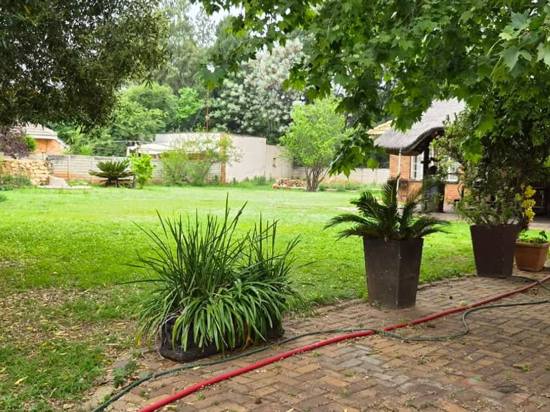 A spacious backyard featuring a paved patio area, established lawn, and mature trees, providing a private outdoor space.