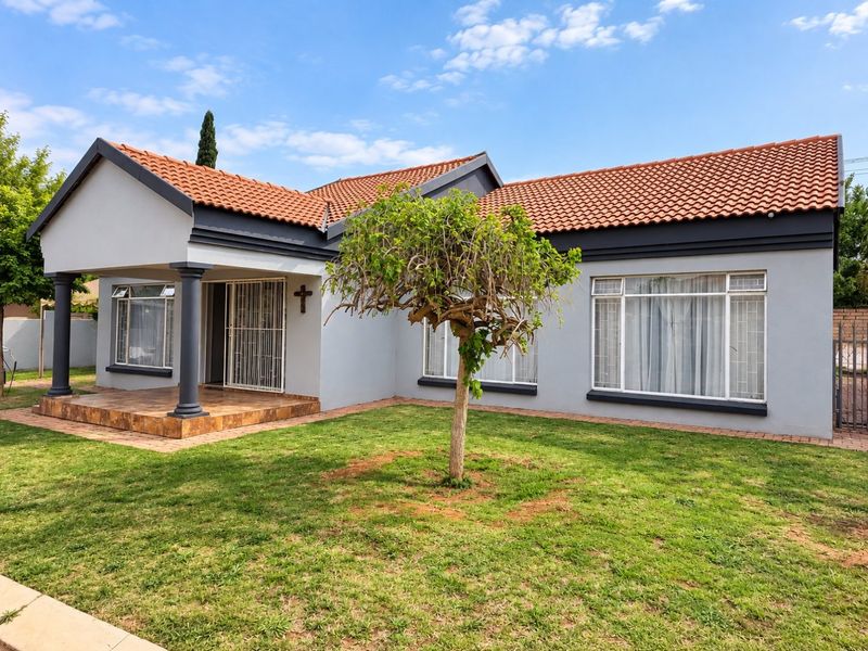 A well-maintained townhouse exterior featuring a terracotta tiled roof, covered front porch with decorative columns, and a neat front garden with paved access.