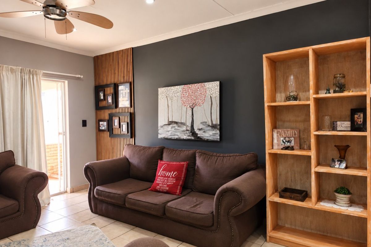 A well-maintained living room featuring a modern slatted wood accent wall, recessed lighting, a ceiling fan, and tiled flooring with access to an outdoor area.