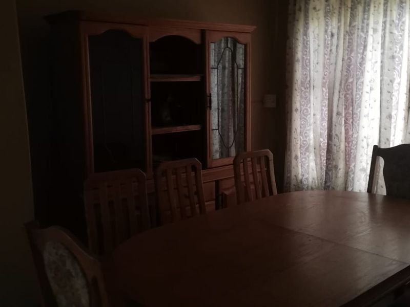 A dimly lit dining room area featuring a window with curtains.