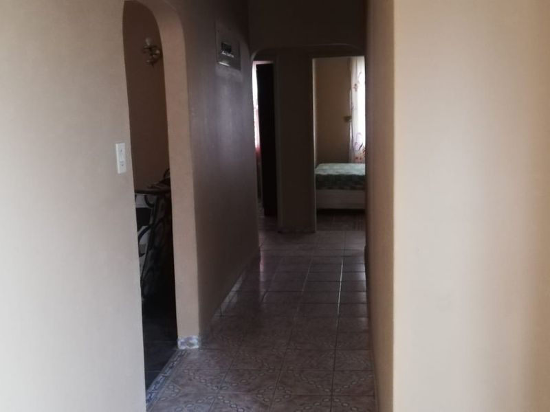 A functional hallway featuring tiled flooring and arched architectural transitions leading to adjacent rooms.