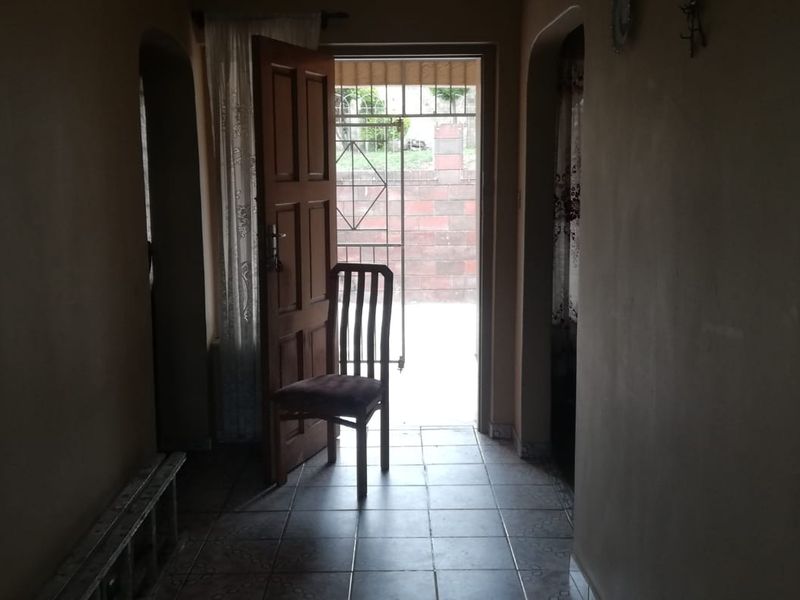 An entry hallway featuring tiled flooring and a security gate, providing access to the exterior of the property.