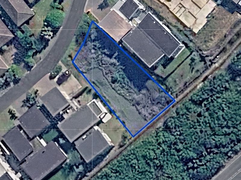 An aerial view of a vacant residential plot situated within a developed neighborhood, highlighting the available land area and surrounding property context.