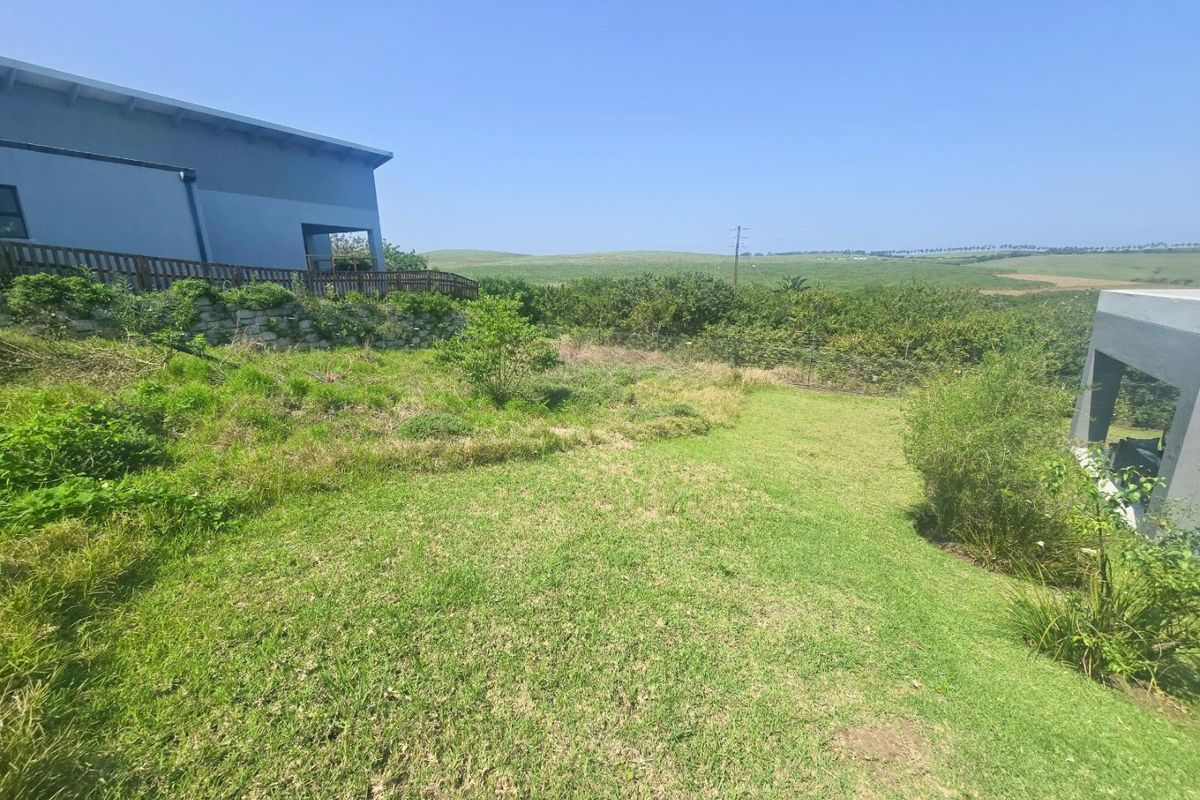 A spacious residential garden area featuring a stone retaining wall, timber decking, and expansive views of the surrounding landscape.