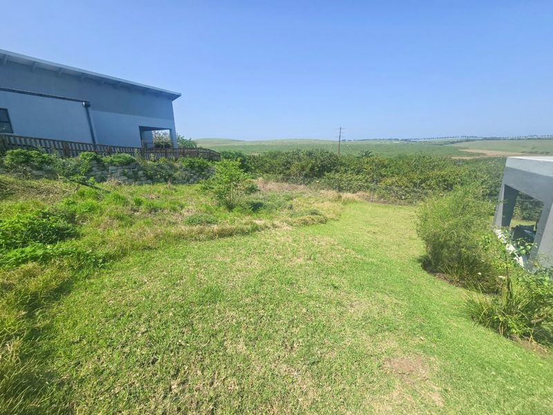 A spacious residential garden area featuring a stone retaining wall, timber decking, and expansive views of the surrounding landscape.