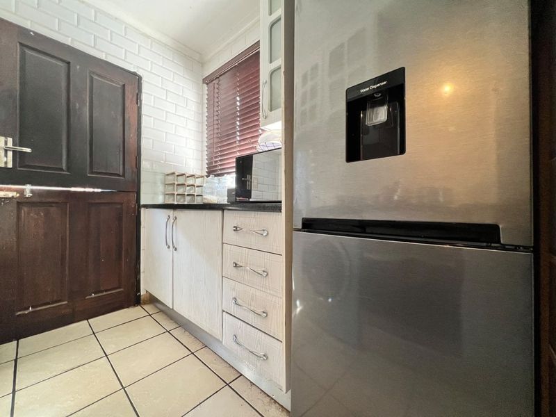 A compact kitchen area featuring built-in cabinetry, subway tile backsplash, and tiled flooring, providing a functional workspace with a classic aesthetic.