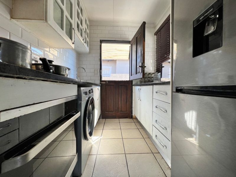 Compact scullery featuring subway tile backsplash, built-in cabinetry, stone countertops, and direct access to the exterior via a stable door.