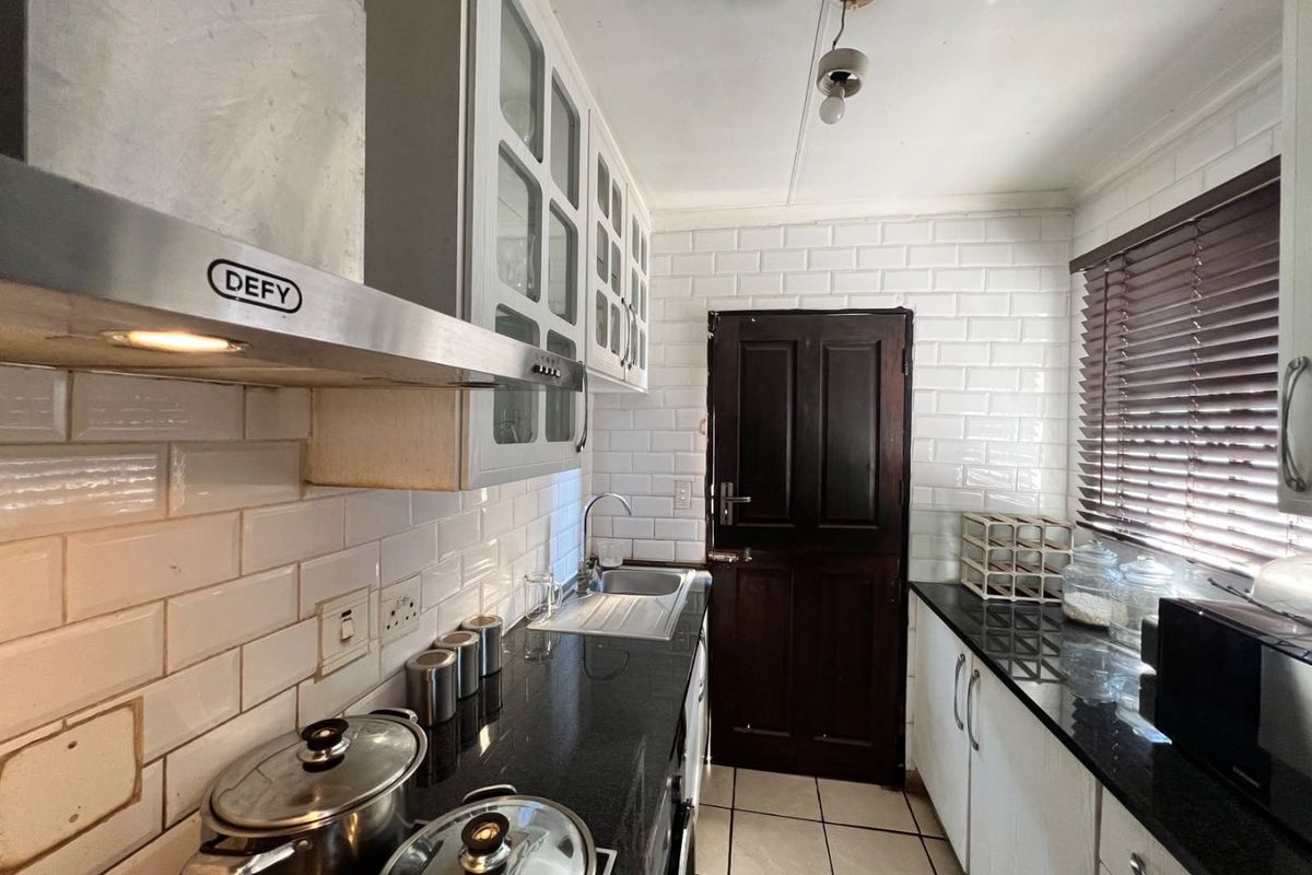Functional kitchen featuring granite countertops, subway tile backsplash, stainless steel extractor fan, and ample cabinetry with a convenient stable door exit.