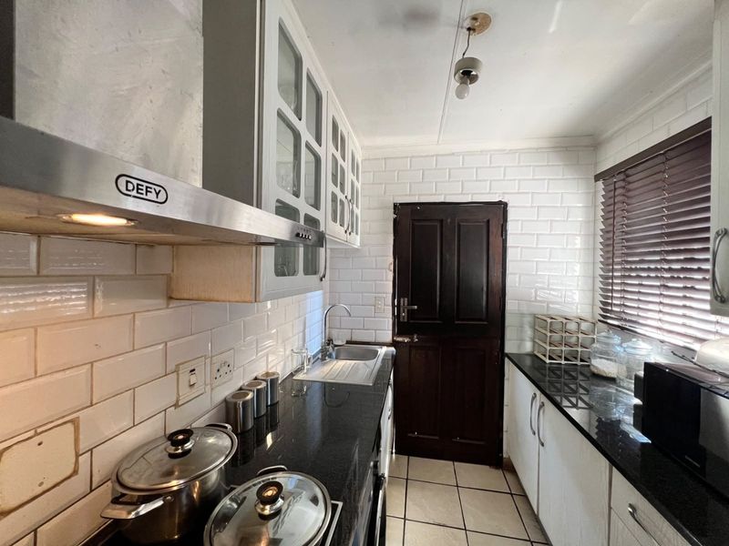 Functional kitchen featuring granite countertops, subway tile backsplash, stainless steel extractor fan, and ample cabinetry with a convenient stable door exit.