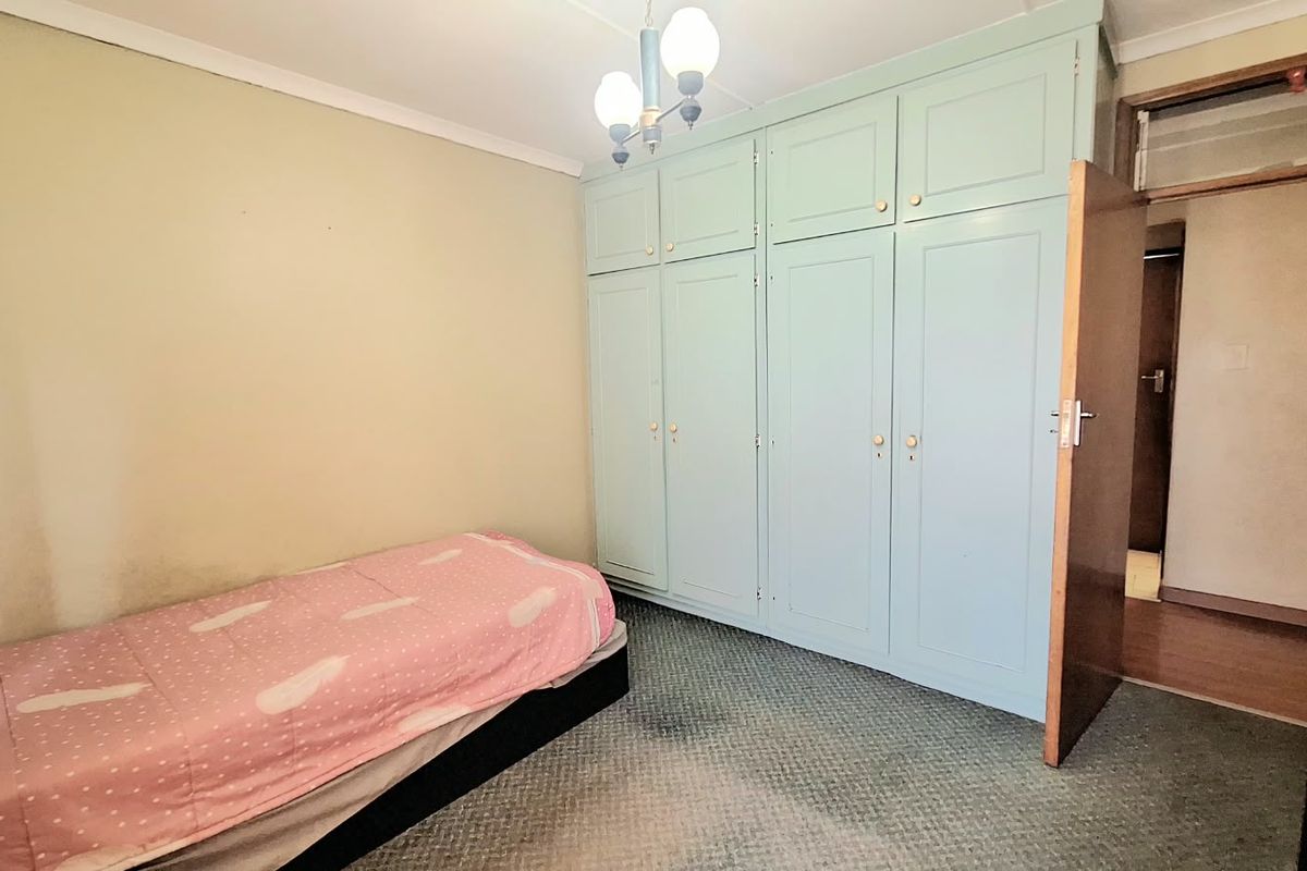 A bedroom featuring built-in cupboards, carpeted flooring, and a ceiling light fixture.