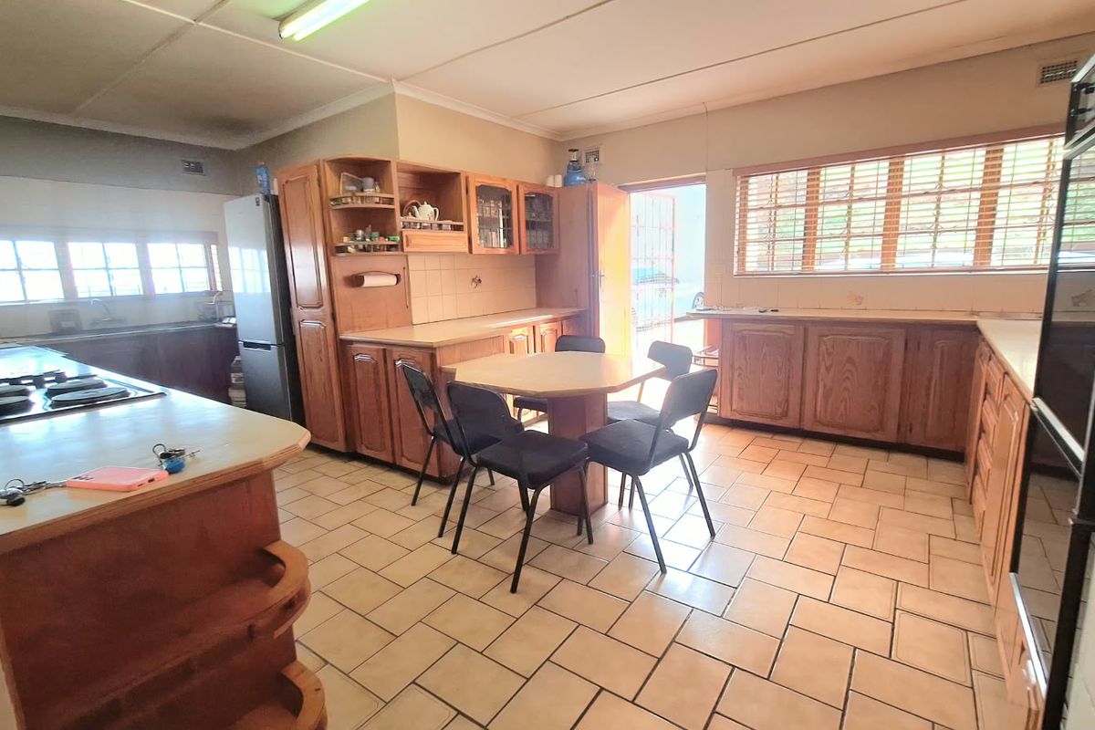 Spacious kitchen featuring extensive wooden cabinetry, tiled flooring, and built-in cooking appliances, offering a functional layout with potential for modern updates.
