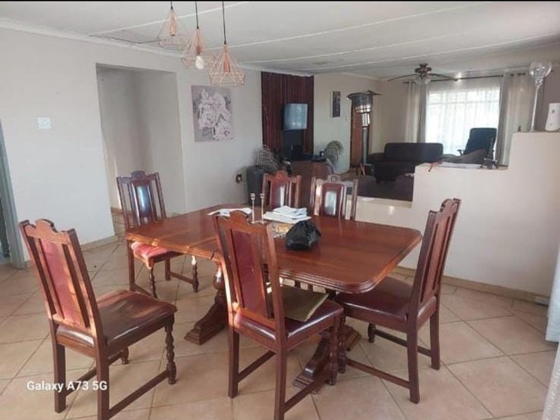 Open plan dining and living area featuring tiled flooring, ceiling fan, and pendant lighting, offering a functional layout for family living.