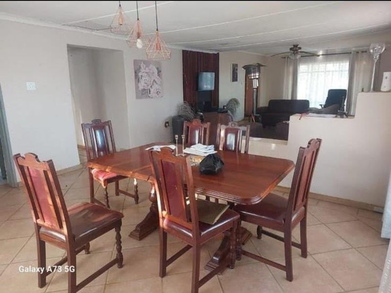 Open plan dining and living area featuring tiled flooring, ceiling fan, and pendant lighting, offering a functional layout for family living.