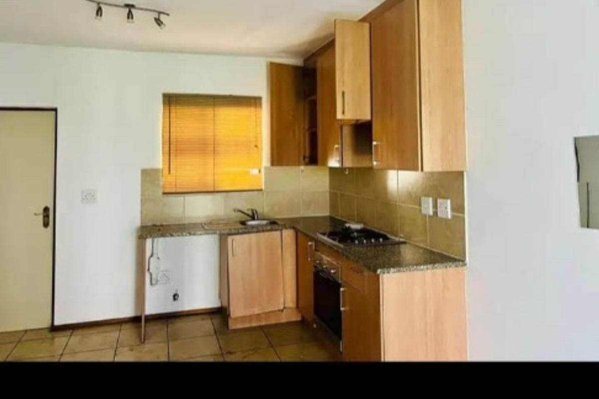 A functional kitchen featuring light wood cabinetry, granite countertops, a built-in oven and hob, and tiled flooring.