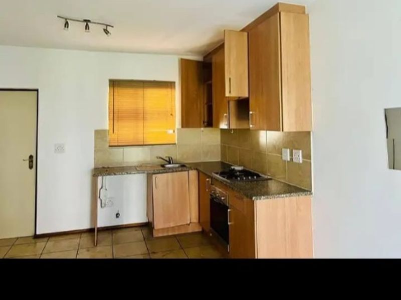 A functional kitchen featuring light wood cabinetry, granite countertops, a built-in oven and hob, and tiled flooring.