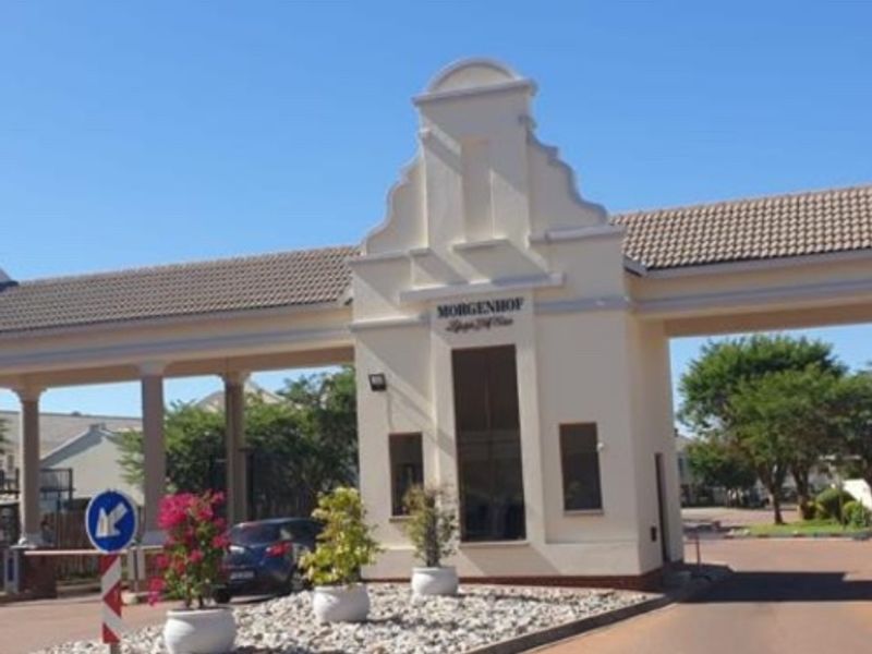 The main entrance and security gatehouse of the Morgenhof estate, featuring a well-maintained facade and paved access road.