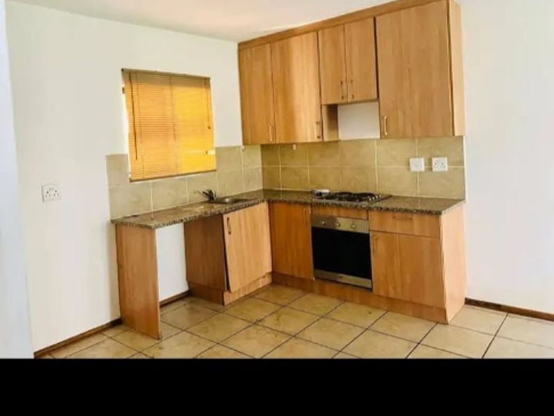 A functional kitchen featuring light wood cabinetry, granite countertops, a built-in oven, and a gas hob with tiled flooring and backsplash.