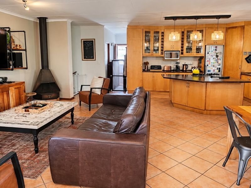 Spacious open-plan living area featuring a kitchen with wooden cabinetry, a central island, and a cozy freestanding fireplace in the lounge section.