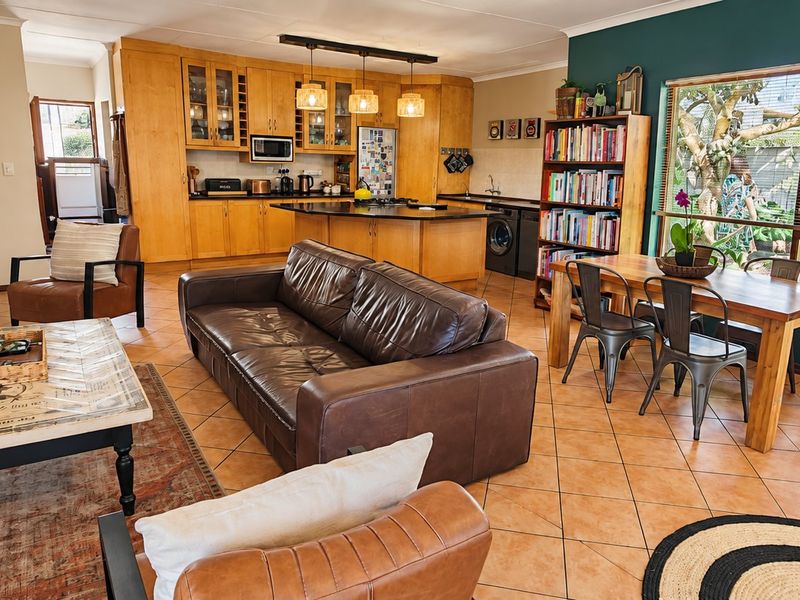 Spacious open-plan living area featuring a functional kitchen with island, dining space, and a cozy fireplace, finished with tiled flooring throughout.