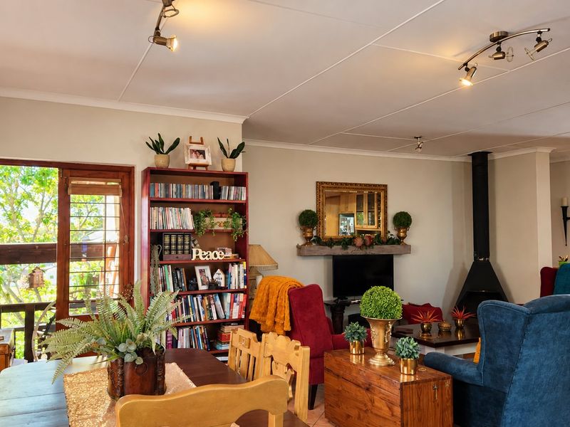 Spacious open-plan living and dining area featuring a freestanding fireplace, tiled flooring, and direct access to an outdoor balcony through timber-framed doors.