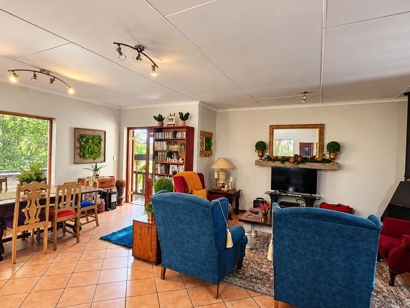 Spacious open-plan living and dining area featuring tiled flooring, a modern freestanding fireplace, and large windows providing ample natural light.