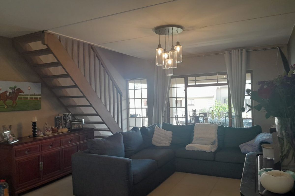 Spacious living room featuring tiled flooring, a wooden staircase, and large sliding glass doors that provide natural light and access to the outdoor area.