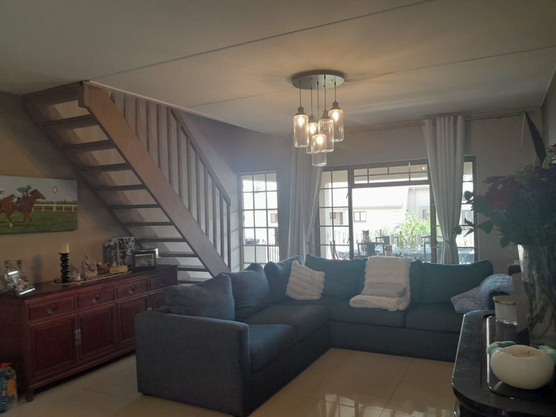 Spacious living room featuring tiled flooring, a wooden staircase, and large sliding glass doors that provide natural light and access to the outdoor area.