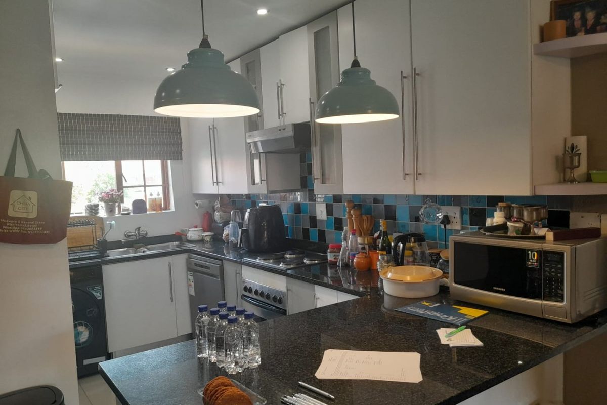 A functional kitchen featuring granite countertops, white cabinetry, a tiled backsplash, and integrated appliances, offering a practical layout for daily cooking and preparation.