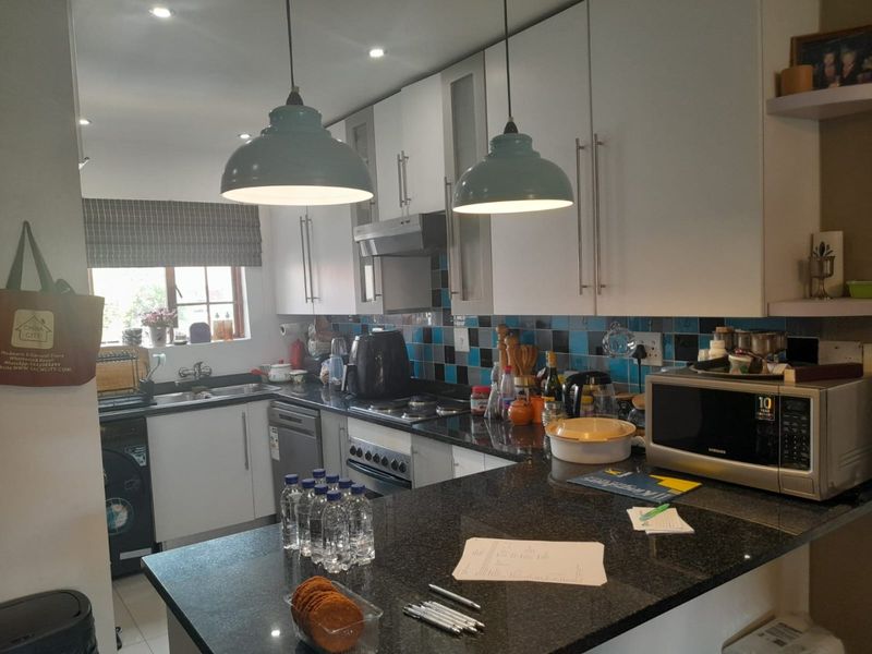A functional kitchen featuring granite countertops, white cabinetry, a tiled backsplash, and integrated appliances, offering a practical layout for daily cooking and preparation.