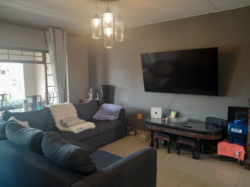 A comfortable living room featuring tiled flooring, modern pendant lighting, and a sliding glass door providing access to an outdoor patio area.
