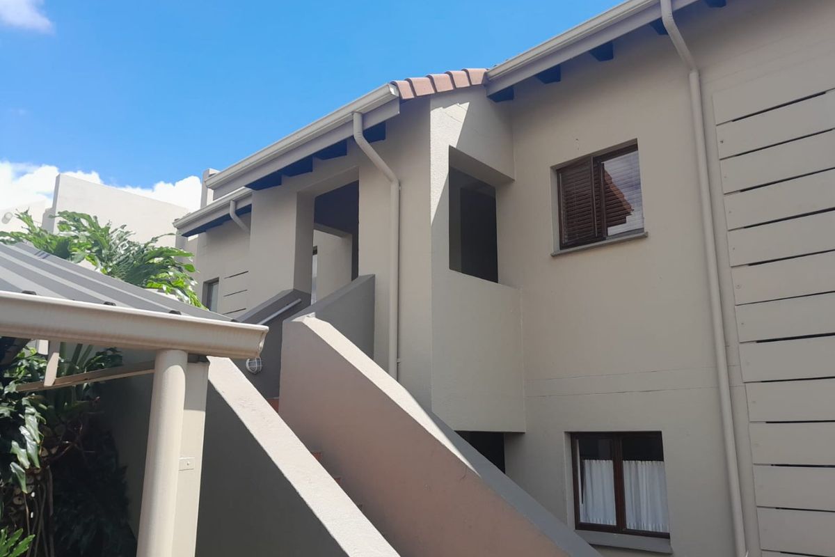 Exterior view of the townhouse rear facade featuring a staircase, tiled roof, and neutral painted walls.