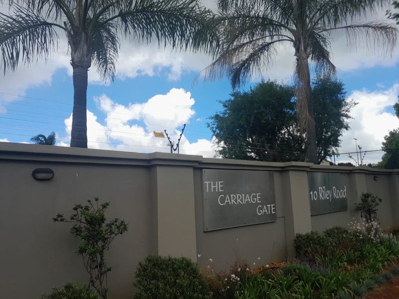 Front perimeter wall of The Carriage Gate complex at 10 Riley Road, featuring secure electric fencing and established landscaping.
