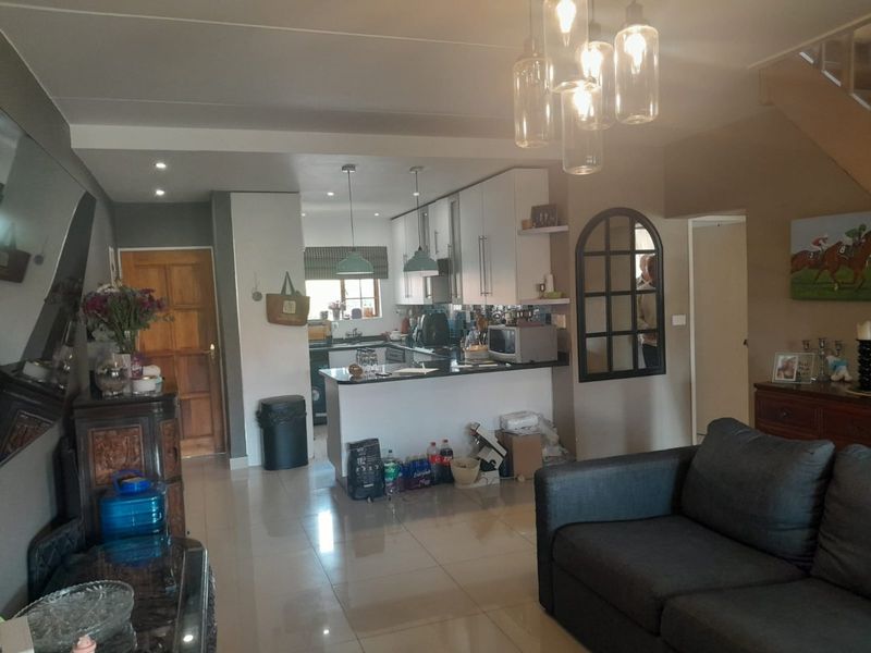 Open-plan living area featuring a functional kitchen with built-in cabinetry, granite countertops, and tiled flooring, seamlessly connected to the main living space.